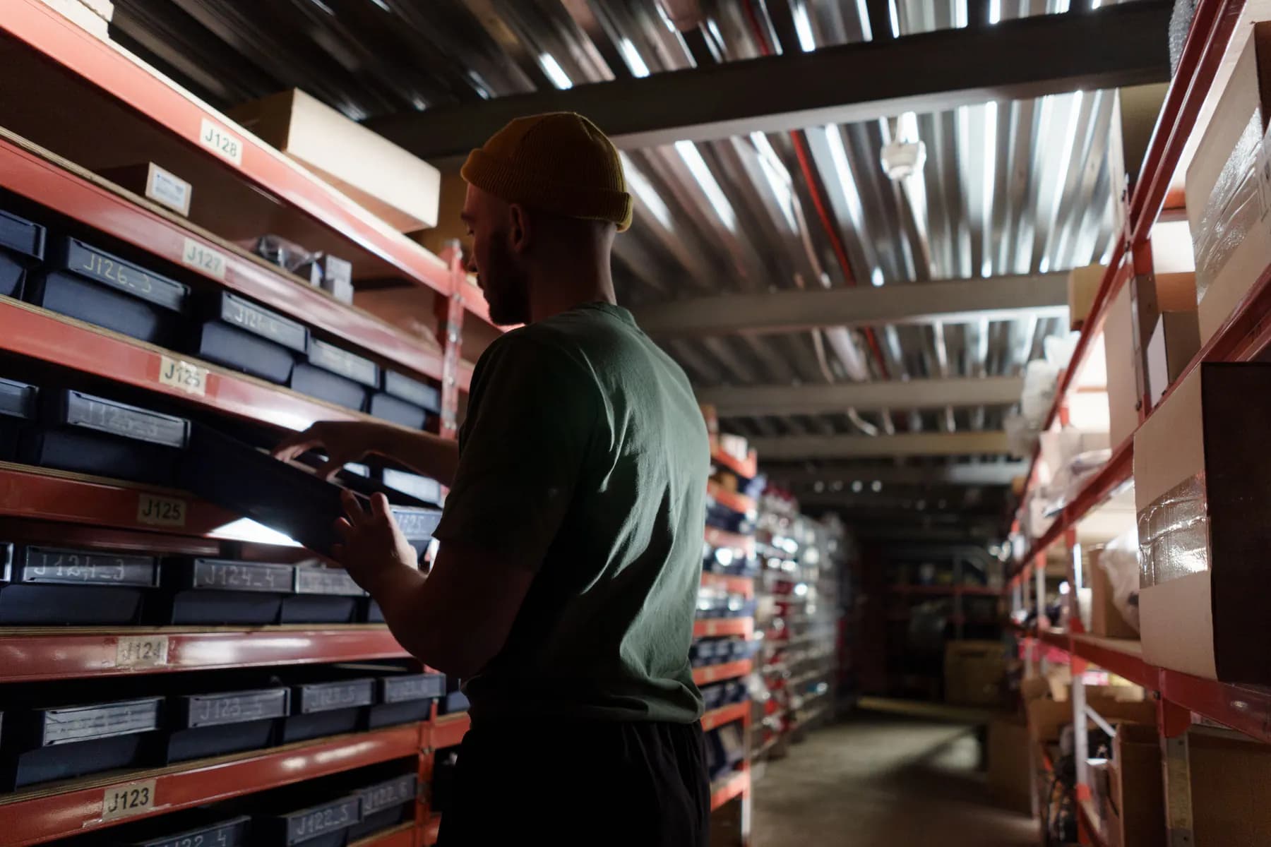 Warehouse operator checking inventory on warmly lit shelves